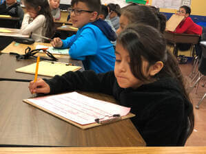 Girl in classroom writing on paper