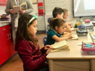 Girl in classroom reading a book